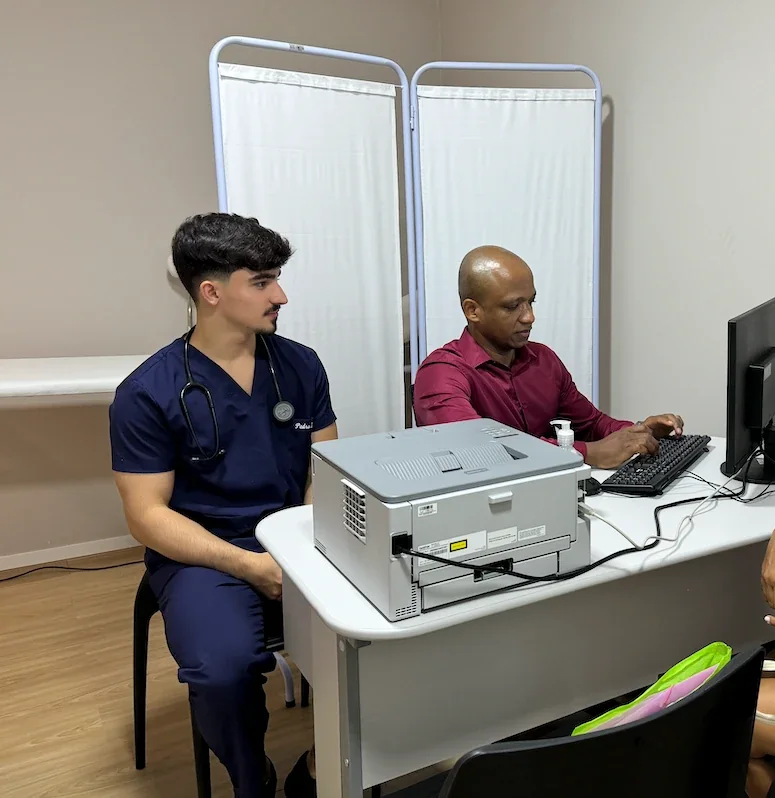 Atendimento em consultório: um aluno de uniforme azul e um professor diante do computador